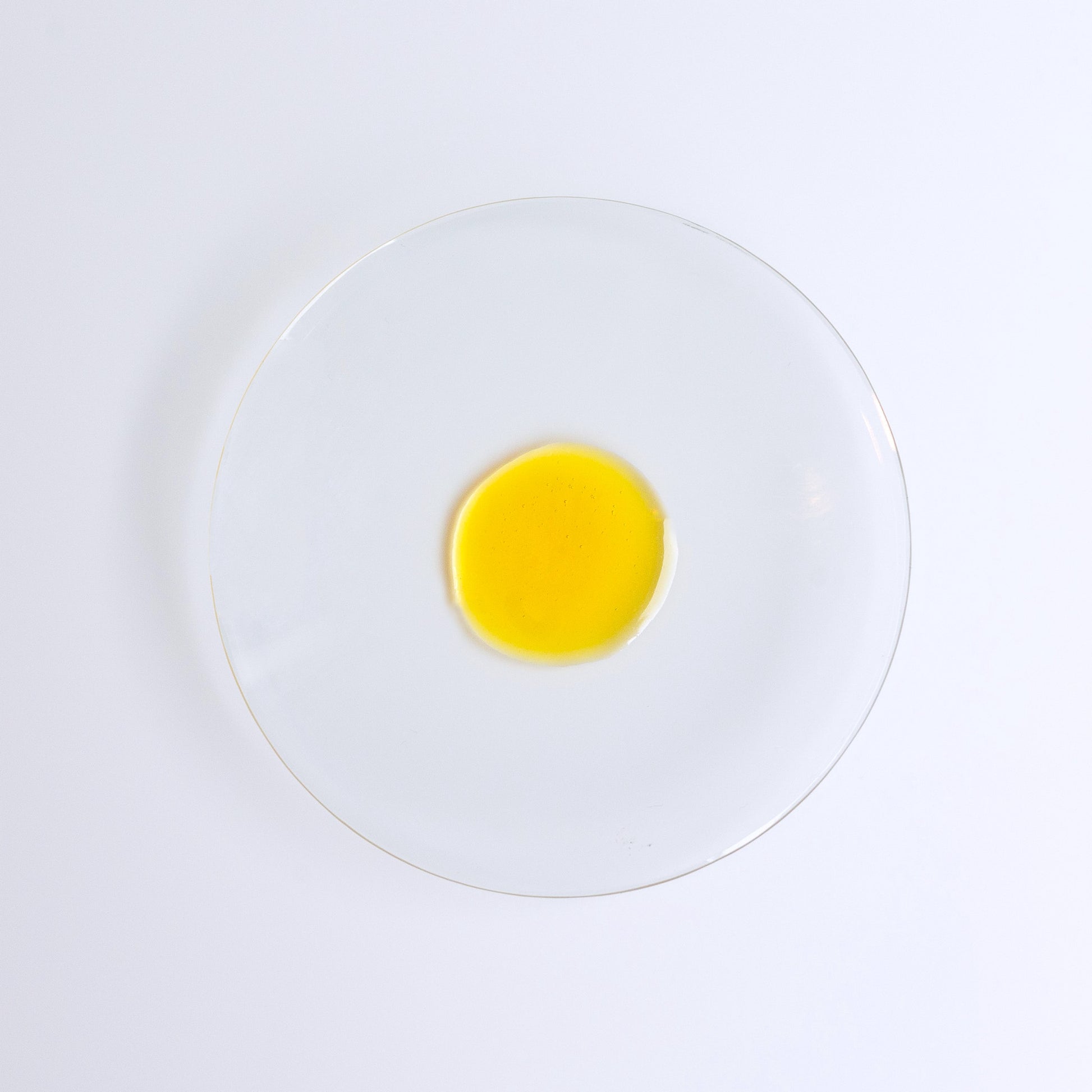 YOU ARE MY SUNSHINE Supercharged Glow Drops, bakuchiol face serum, single drop of golden liquid on a glass dish.