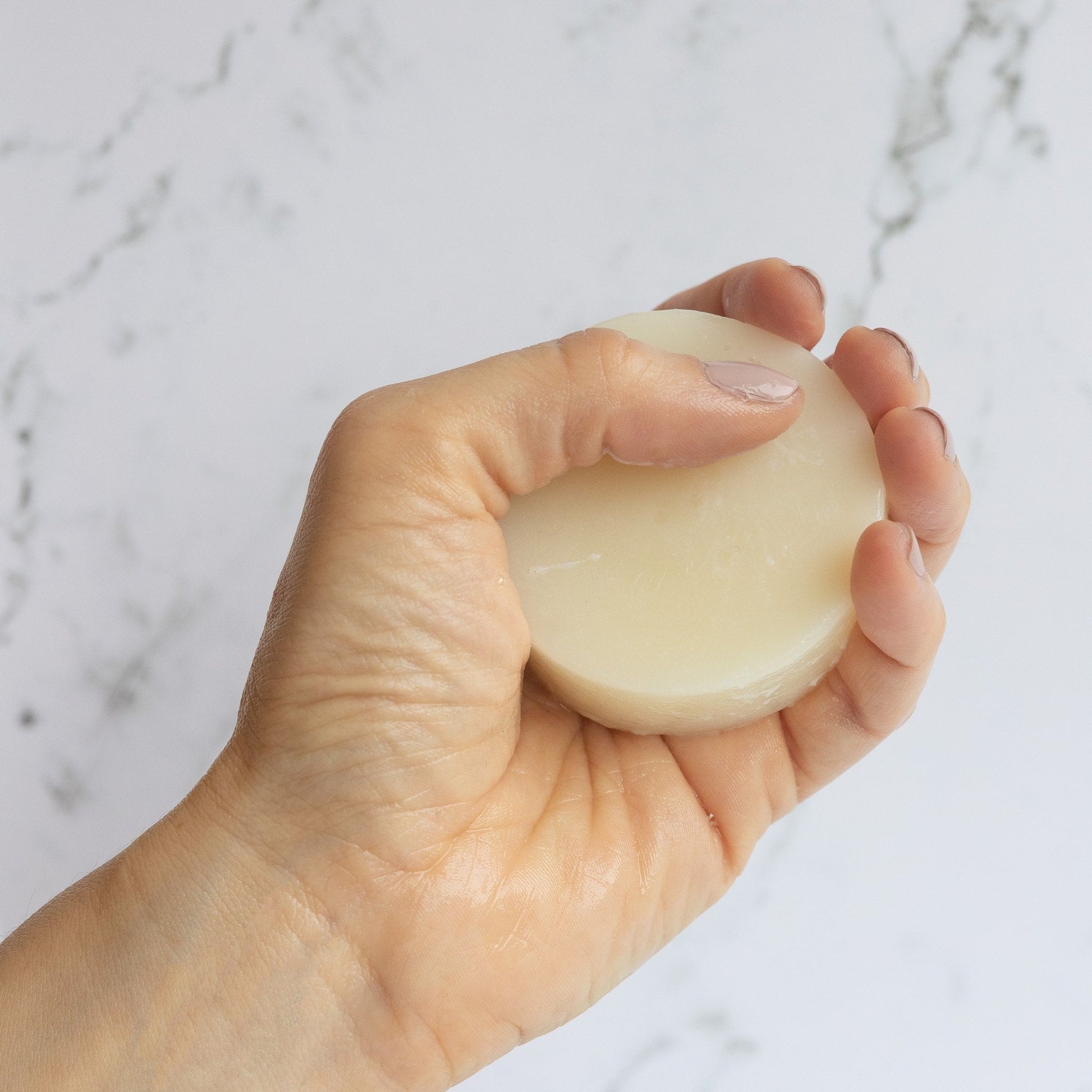 GOOD HAIR DAYS Supercharged Conditioner Bar for dry or damaged hair. Round pale yellow puck wet in hand.