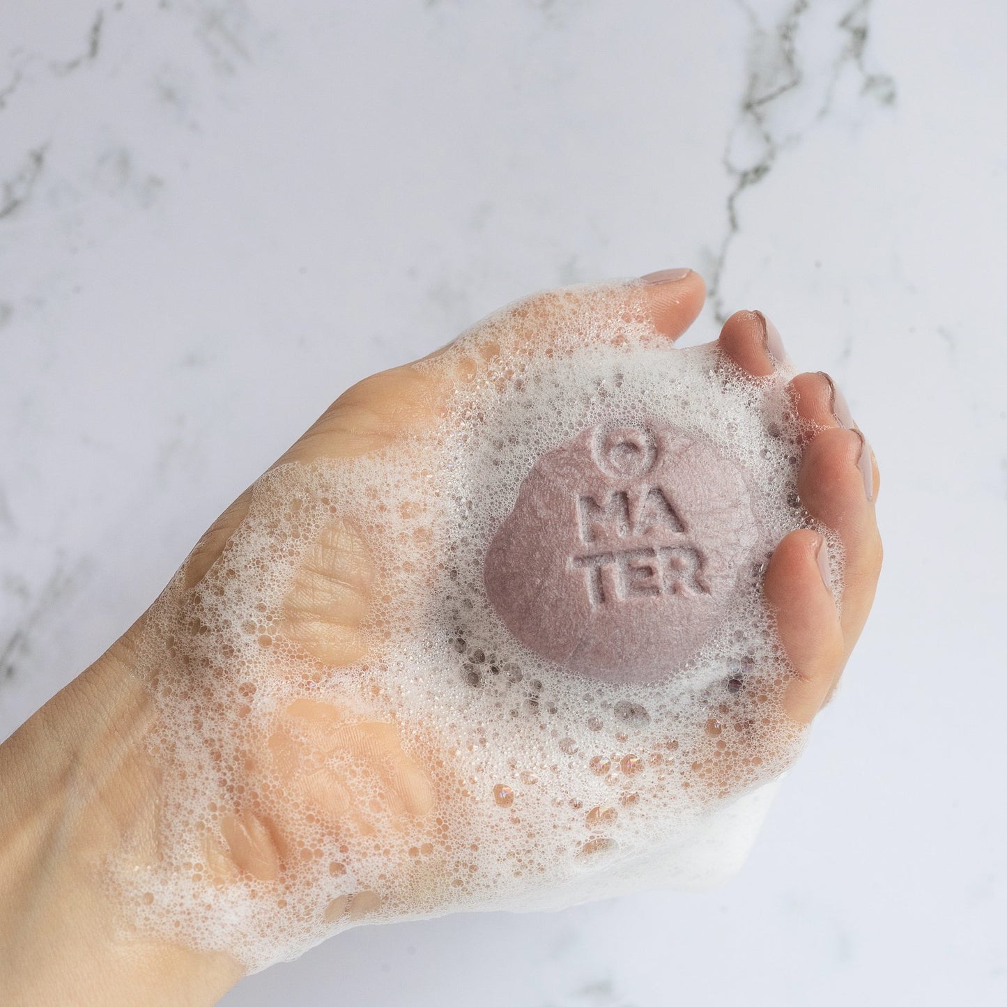 T.L.C. Nourishing Shampoo Bar for dry, damaged or coloured hair. Round pale purple puck with abundant lather in hand.